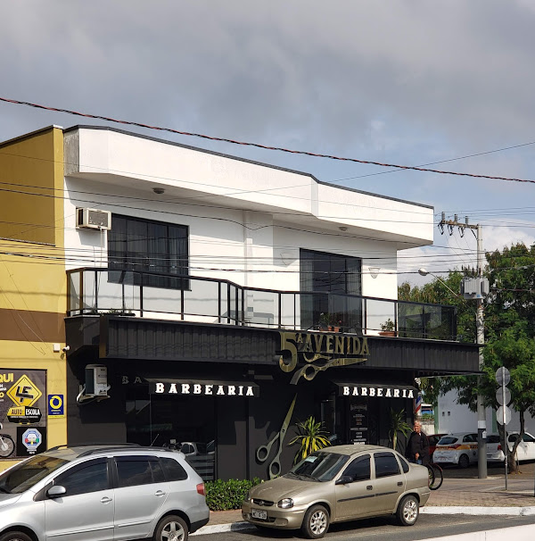 Fachada preta e dourada da 5ª Avenida Barbearia
